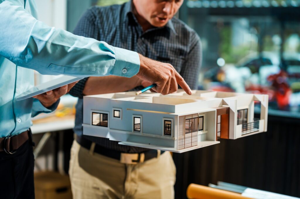 A Caucasian male engineer and an Italian male building contractor planning and talking at desk